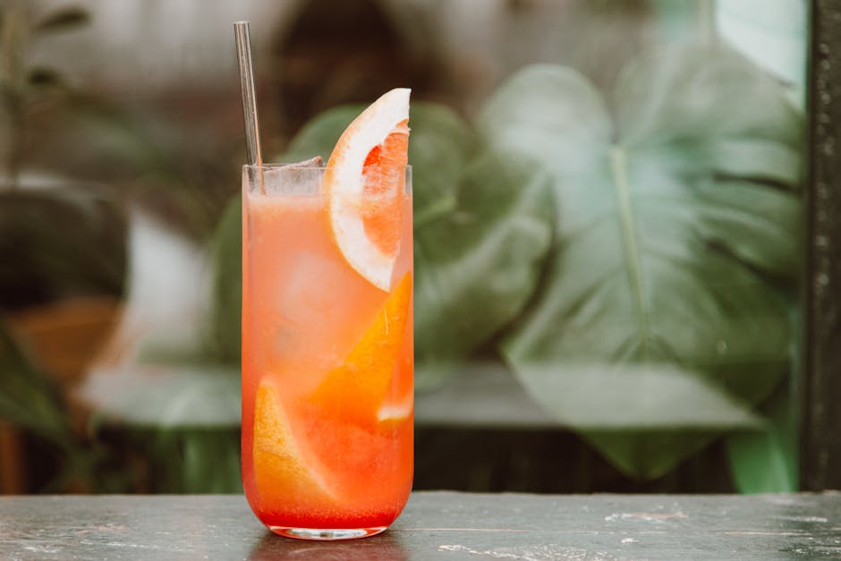 Fresh orange juice with pulp beside whole citrus fruit